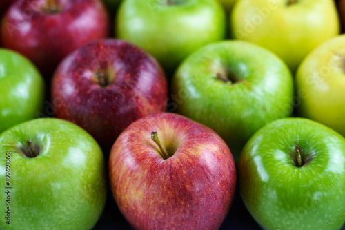 Grupo de manzanas de diferentes colores y variedades dispuestas en fila con desenfoque del fondo.