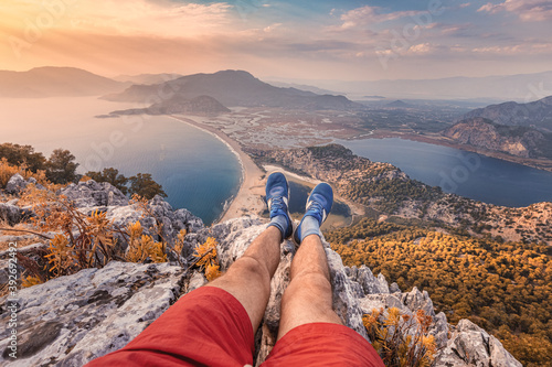 Fotografie Young man ran up the mountain with a great view of the seascape and let his legs rest