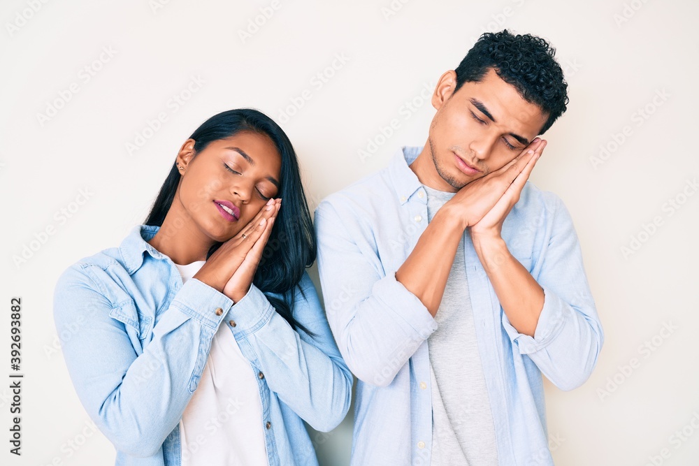 Beautiful latin young couple wearing casual clothes sleeping tired dreaming and posing with hands together while smiling with closed eyes. Beautiful latin young couple wearing casual clothes sleeping tired dreaming and posing with hands together while smiling with closed eyes.