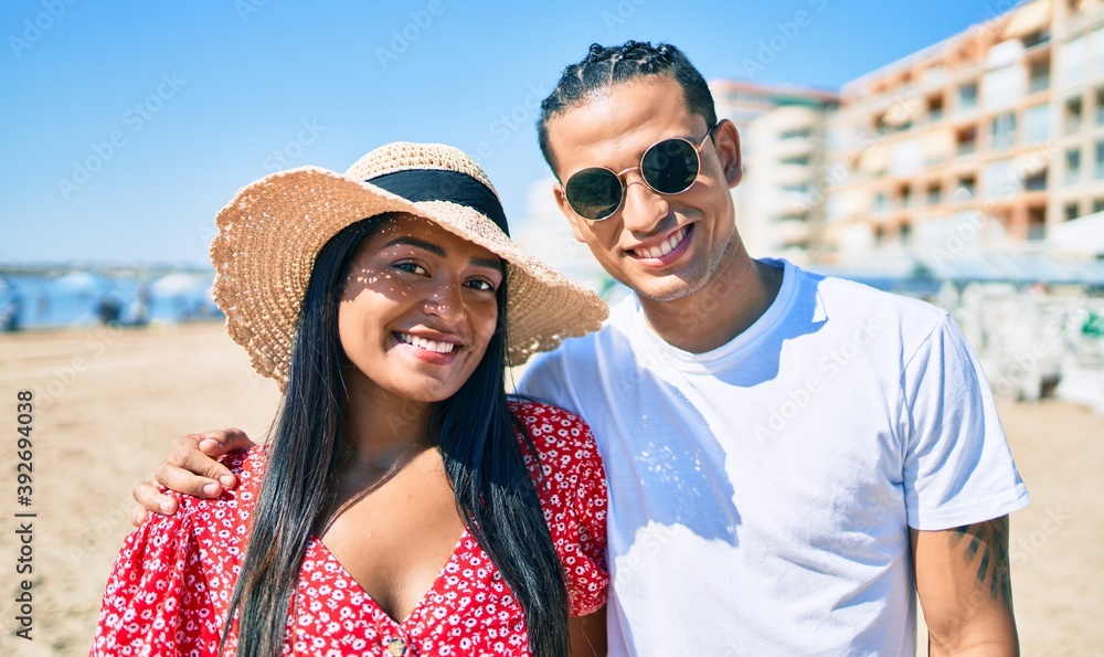 Obraz premium Young latin couple smiling happy and hugging at the beach.