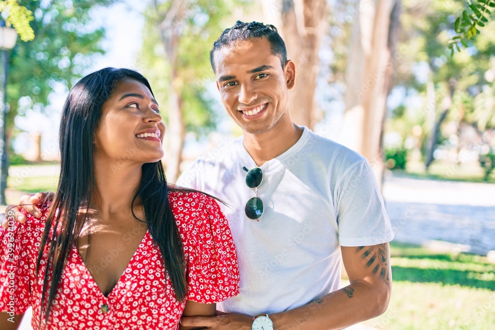 Fototapeta premium Young latin couple smiling happy and hugging at the park.