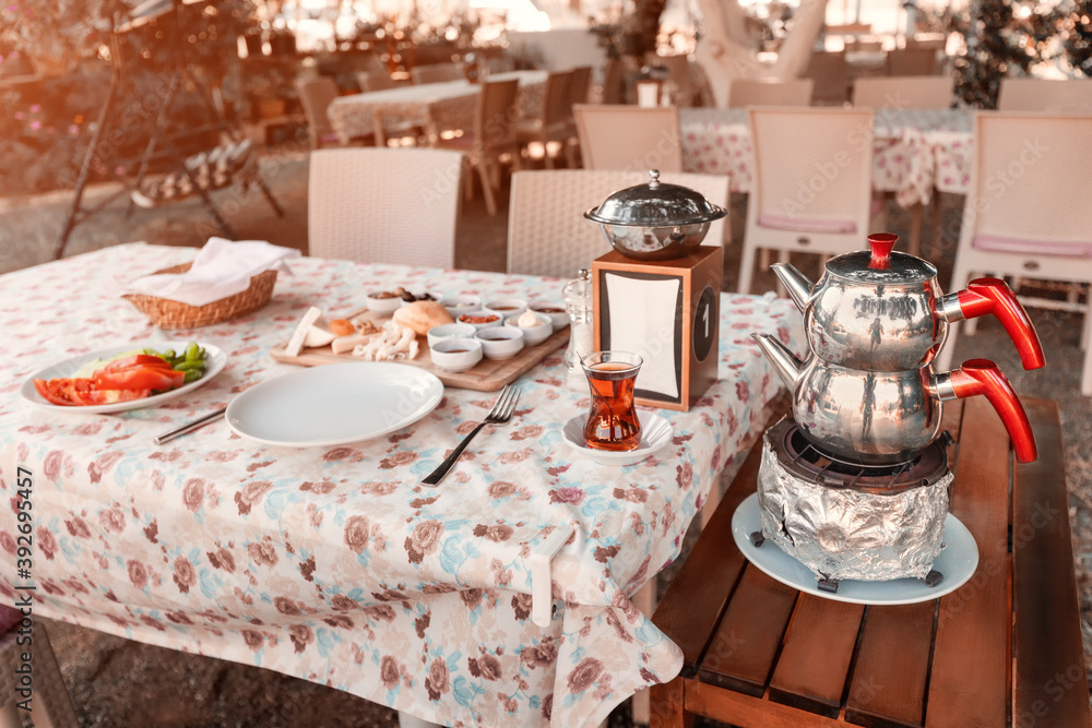 Rich and tasty Turkish breakfast with cheese and appetizers, fresh vegetables and an authentic double teapot for brewing and boiling water.