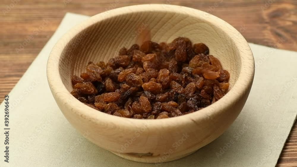 Raisins falling into a wooden bowl, slow motion Raisins falling into a wooden bowl, slow motion