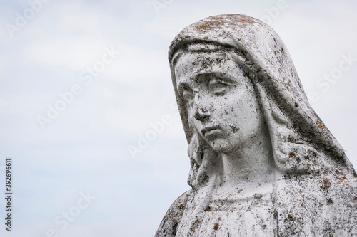 A old sculpture of Virgin Mary. The stone statue is partially destroyed by time. (faith concept)