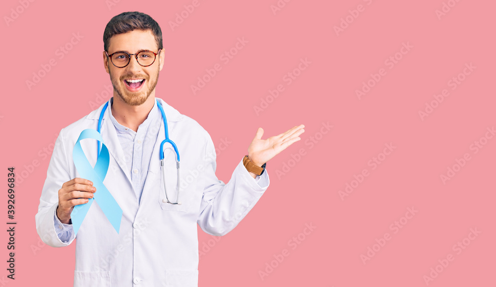 Handsome young man with bear wearing doctor uniform and holding blue ribbon celebrating victory with happy smile and winner expression with raised hands Handsome young man with bear wearing doctor uniform and holding blue ribbon celebrating victory with happy smile and winner expression with raised hands