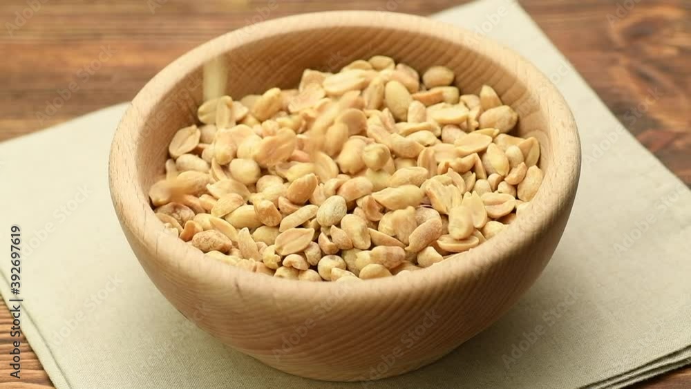 Peanuts falling into a wooden bowl, slow motion Peanuts falling into a wooden bowl, slow motion