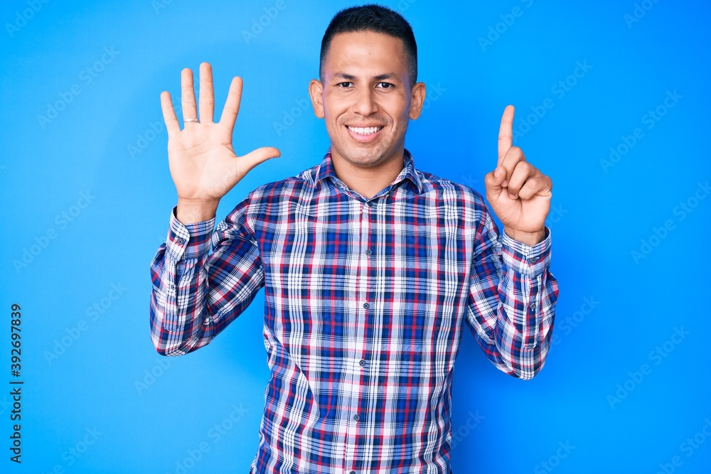 Young handsome latin man wearing casual clothes showing and pointing up with fingers number six while smiling confident and happy. Young handsome latin man wearing casual clothes showing and pointing up with fingers number six while smiling confident and happy.