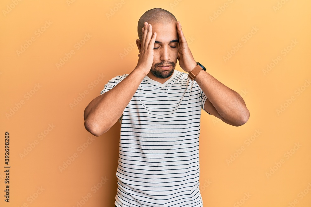 Hispanic adult man wearing casual clothes with hand on head, headache because stress. suffering migraine. Hispanic adult man wearing casual clothes with hand on head, headache because stress. suffering migraine.