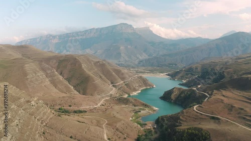 Picturesque Gizhgit blue lake in mountain valley on summit landscape. Drone shooting amazing lake among brown mountain in Kabardino Balkaria. Car road on highlands foot on lake shore photo