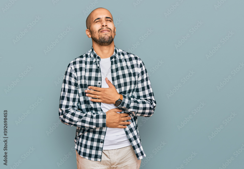 Hispanic adult man wearing casual clothes with hand on stomach because nausea, painful disease feeling unwell. ache concept. Hispanic adult man wearing casual clothes with hand on stomach because nausea, painful disease feeling unwell. ache concept.