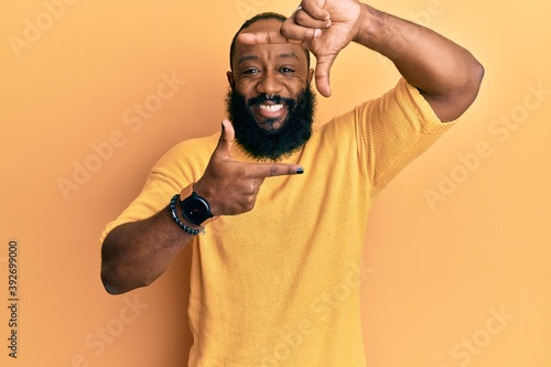 Young african american man wearing casual clothes smiling making frame with hands and fingers with happy face. creativity and photography concept.