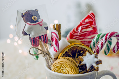 Christmas sweet food. Delicious Christmas sweets cookies, nuts, canes, marshmallows, candies in a grey mug close up