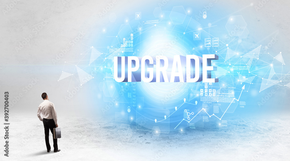 Rear view of a businessman standing in front of UPGRADE inscription, modern technology concept Rear view of a businessman standing in front of UPGRADE inscription, modern technology concept