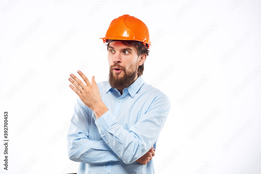 A man in an orange helmet shirt construction industry worked light background A man in an orange helmet shirt construction industry worked light background
