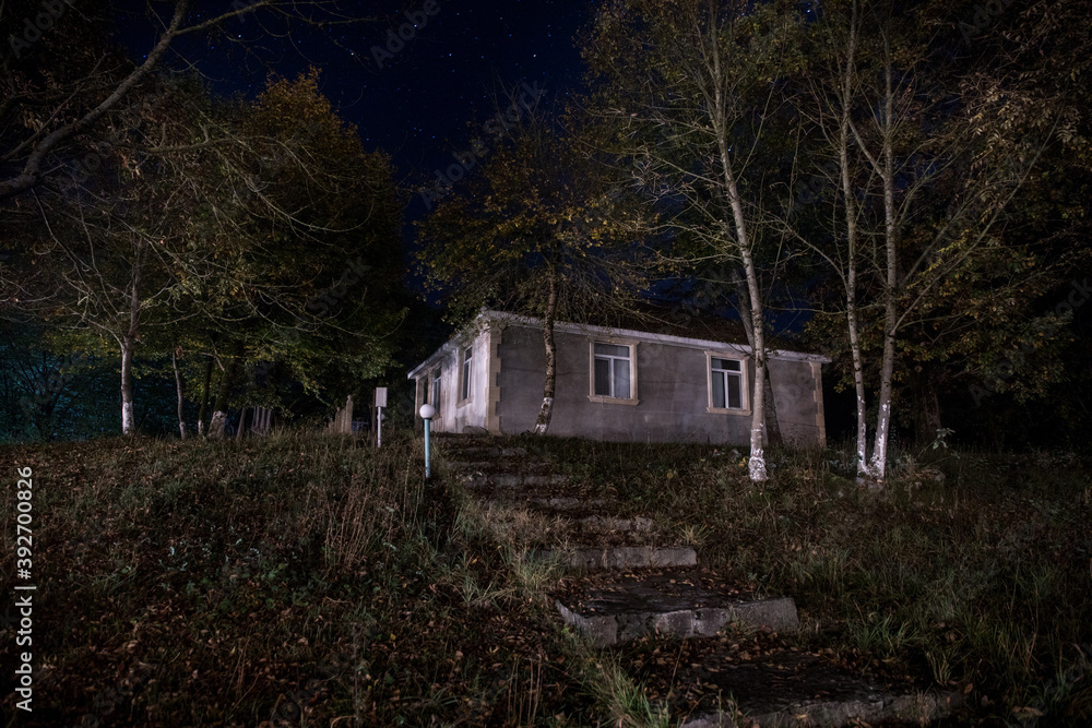 Mountain night landscape of building at forest at night with moon or vintage country house at night with clouds and stars. Summer night. Mountain night landscape of building at forest at night with moon or vintage country house at night with clouds and stars. Summer night.