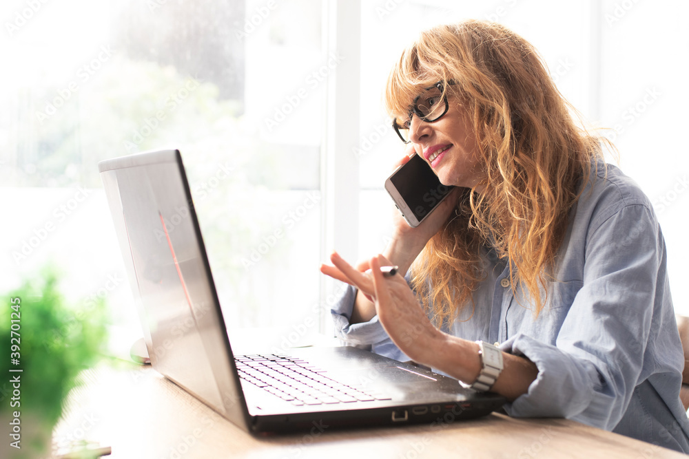 adult woman in office or at home with computer and mobile phone adult woman in office or at home with computer and mobile phone