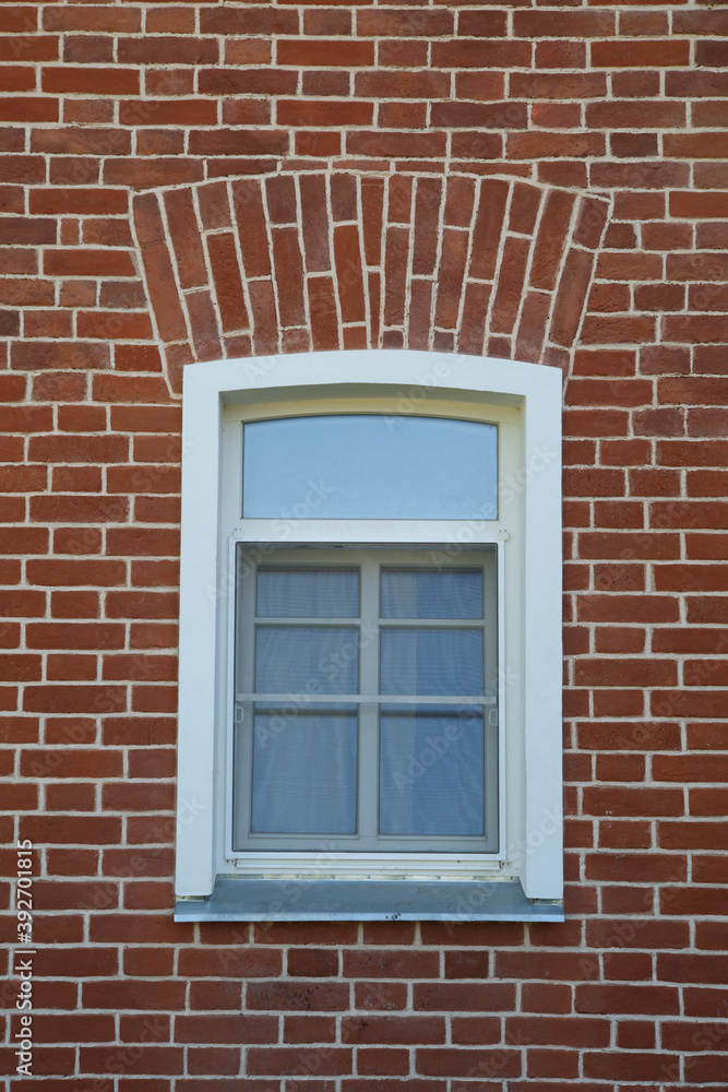 A window with a white frame on a red brick wall.