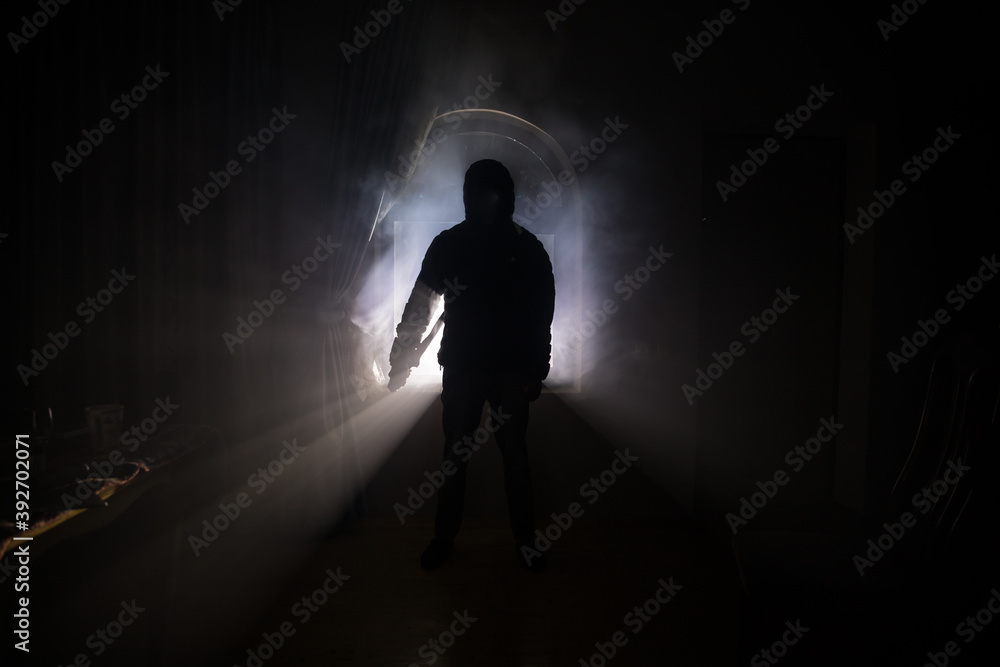 Silhouette of an unknown shadow figure on a door through a closed glass door. The silhouette of a human in front of a window at night.
