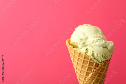 Delicious ice cream in waffle cone on pink background, closeup. Space for text