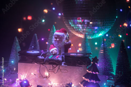Dj mixer with headphones on dark nightclub background with Christmas tree New Year Eve. Close up view of New Year elements on a Dj table. Holiday party concept. Empty space