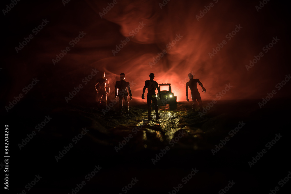 Fototapeta premium photo of a car stopped on the road lighting up a zombies. Silhouette terrible zombie night near the car. Miniature decoration.
