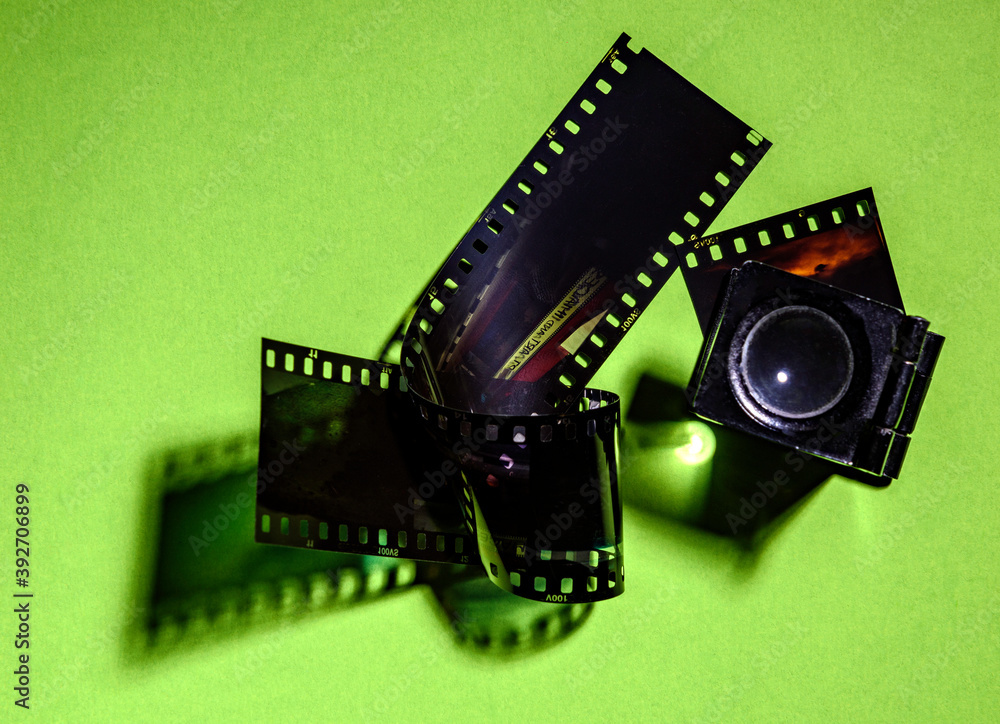 A twisted 35mm strip of film with magnifier on a green background