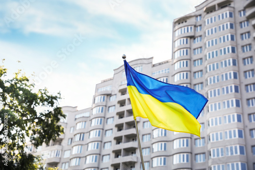 National flag of Ukraine fluttering near building on sunny day photo