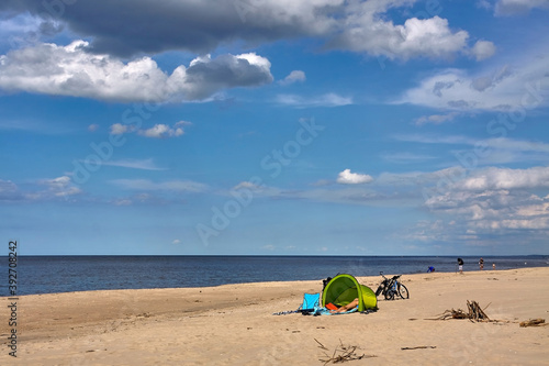 Unrecognizable tourist resting in a green beach tent on a Baltic Sea beach in summer.