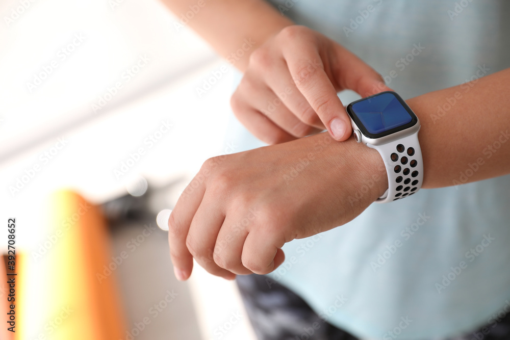 Woman checking fitness tracker in gym, closeup