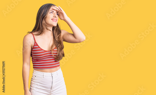 Beautiful caucasian young woman wearing casual clothes very happy and smiling looking far away with hand over head. searching concept.