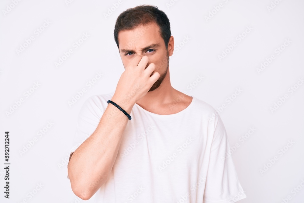 Young handsome man wearing casual white tshirt tired rubbing nose and eyes feeling fatigue and headache. stress and frustration concept. Young handsome man wearing casual white tshirt tired rubbing nose and eyes feeling fatigue and headache. stress and frustration concept.