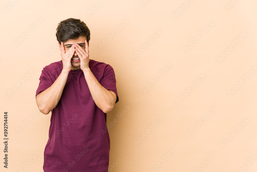 Young cool man blink at the camera through fingers, embarrassed covering face. Young cool man blink at the camera through fingers, embarrassed covering face.