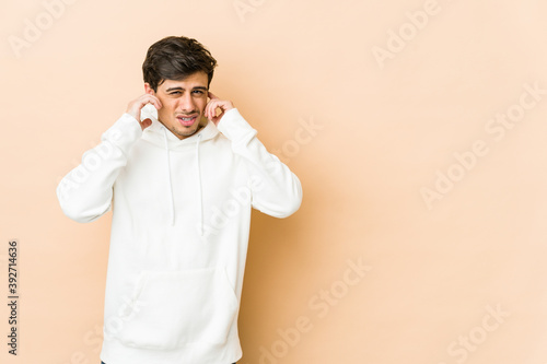 Young cool man covering ears with fingers, stressed and desperate by a loudly ambient.