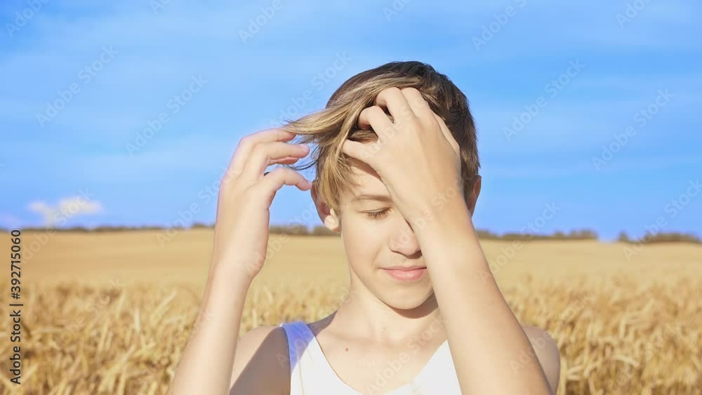 portrait of a boy with a stylish hairstyle combing his head and looking at the camera at the wheat field portrait of a boy with a stylish hairstyle combing his head and looking at the camera at the wheat field