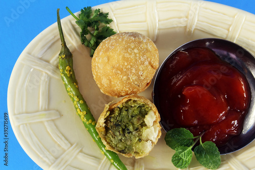 traditional indian gujarati food snack vegetable kachori,vegetable stuffed balls or patties with tomato sause in blue background photo