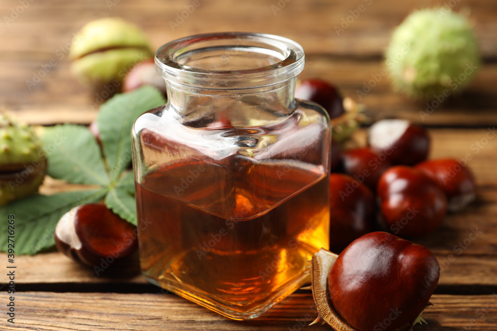 Chestnuts and jar of essential oil on wooden table Chestnuts and jar of essential oil on wooden table