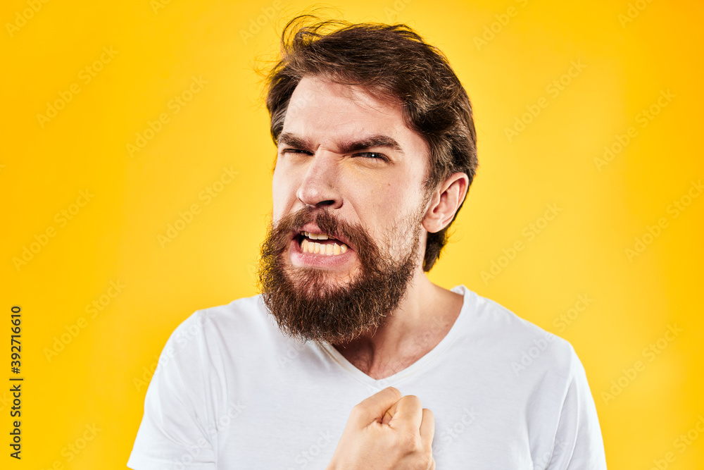 Fototapeta premium emotional bearded man gesturing with hands aggression discontent close-up yellow background