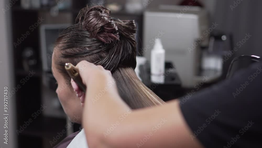 Young woman hairdresser dries with a hairdryer and combs the hair of a client in a beauty salon. Close-up. Young woman hairdresser dries with a hairdryer and combs the hair of a client in a beauty salon. Close-up.
