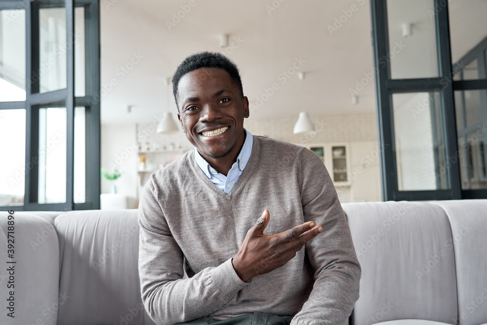 Happy african man online coach, distance applicant looking at camera or web cam video conference calling virtual webcam chat interview meeting sitting on couch at home. Headshot portrait. Stock