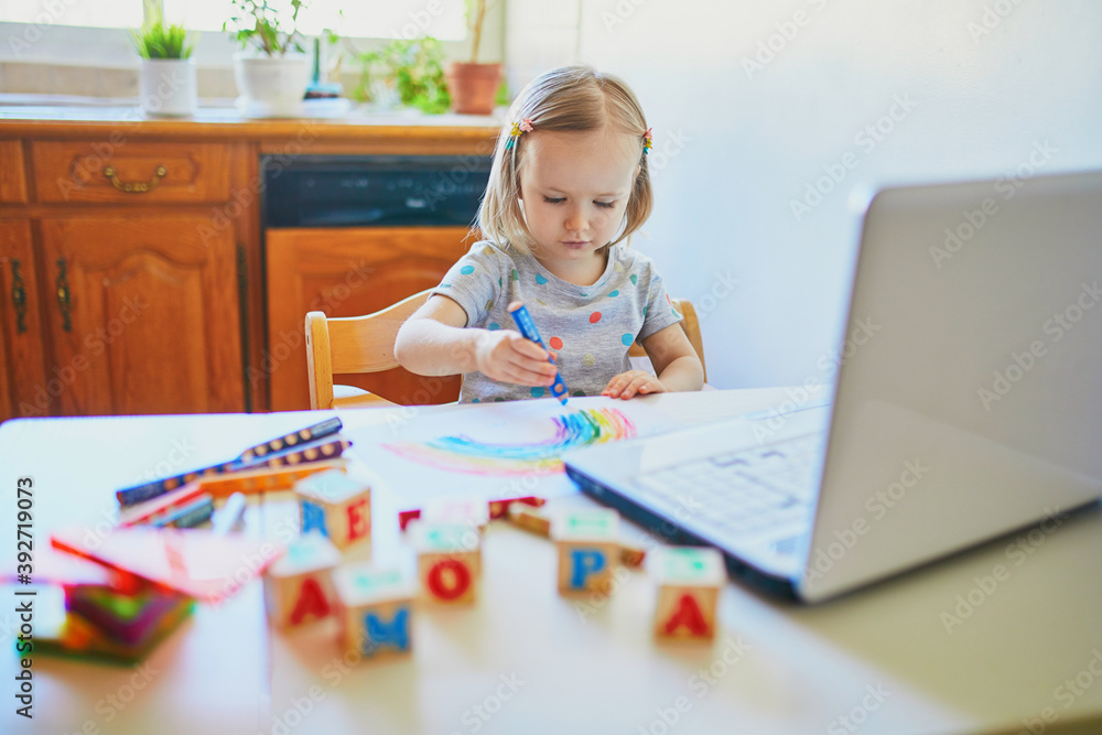 Toddler girl drawing rainbow in front of laptop Toddler girl drawing rainbow in front of laptop