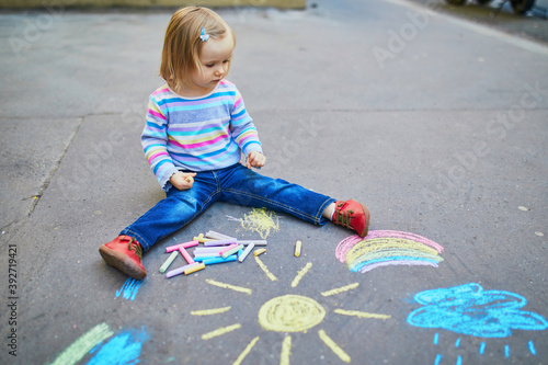 Adorable toddler girl drawing with colorful chalks