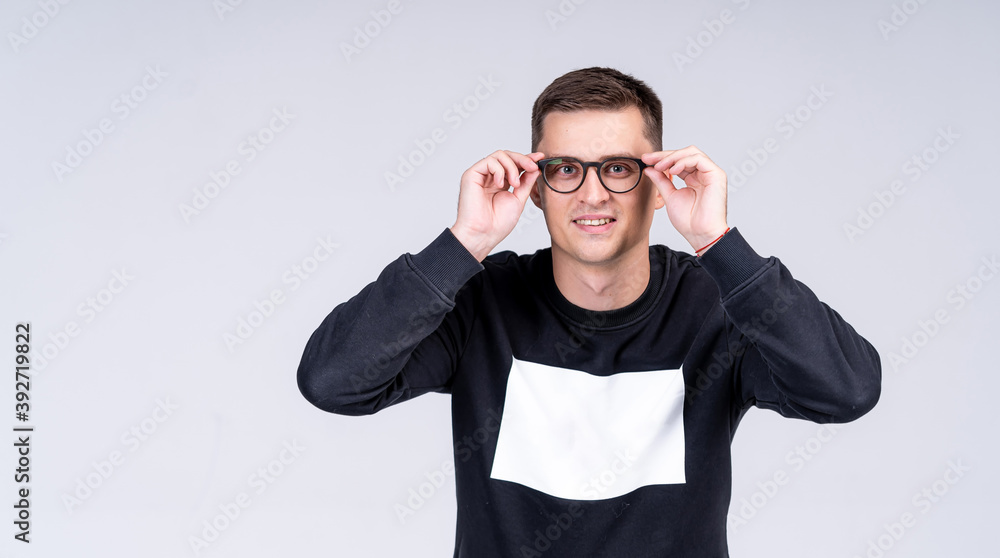 Naklejka premium Handsome man presenting modern glasses on light gray background. Casual sweater with copy space.