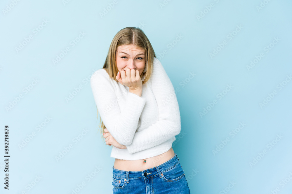 Young blonde woman isolated on blue background biting fingernails, nervous and very anxious. Young blonde woman isolated on blue background biting fingernails, nervous and very anxious.