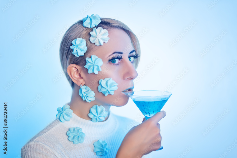 Beautiful woman with meringue candies on her hair holds a sweet blue cocktail Beautiful woman with meringue candies on her hair holds a sweet blue cocktail