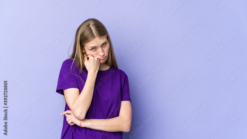Young blonde woman isolated on purple background who feels sad and pensive, looking at copy space. Young blonde woman isolated on purple background who feels sad and pensive, looking at copy space.