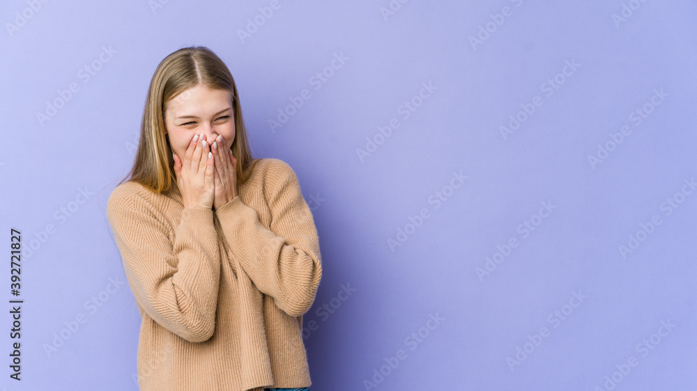 Young blonde woman isolated on purple background laughing about something, covering mouth with hands. Young blonde woman isolated on purple background laughing about something, covering mouth with hands.