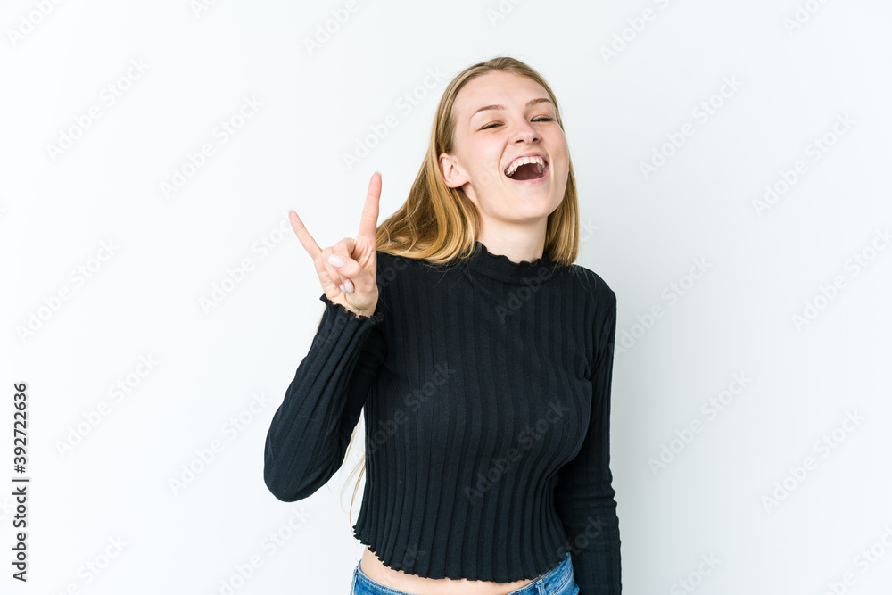 Young blonde woman isolated on white background showing a horns gesture as a revolution concept. Young blonde woman isolated on white background showing a horns gesture as a revolution concept.