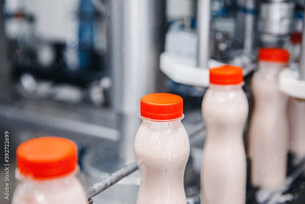 Dairy production, bottle of yoghurt on automated conveyor line, process of milk filling and packaging Dairy production, bottle of yoghurt on automated conveyor line, process of milk filling and packaging