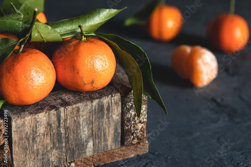 Box with tasty juicy tangerines in wood box on dark background with copy space