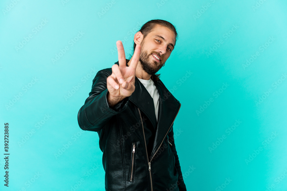 Fototapeta premium Young man with long hair look showing victory sign and smiling broadly.